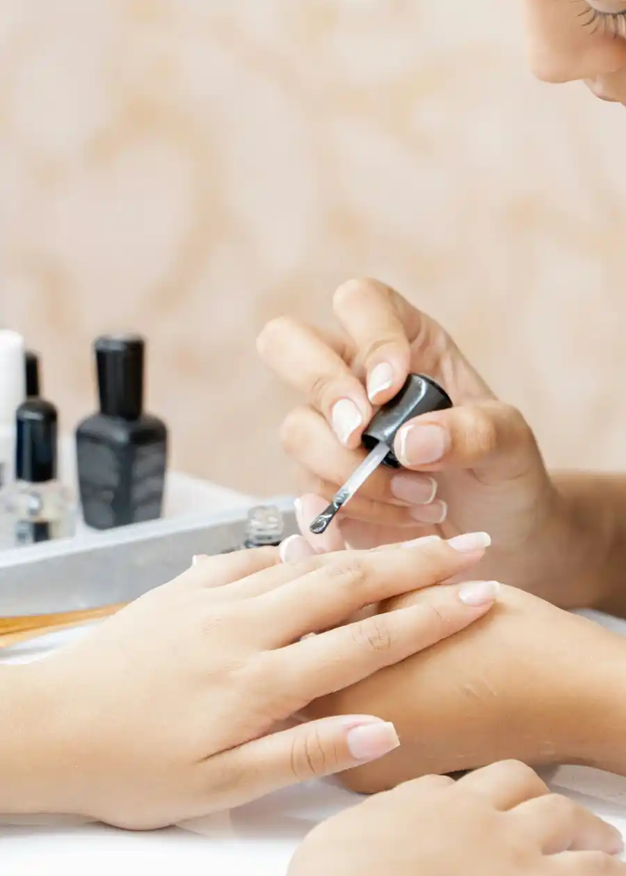 Le mani della manicurista che stendono lo smalto sull'unghia di una cliente